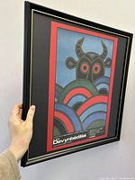 Framed poster held upright showing the front view and artwork details.