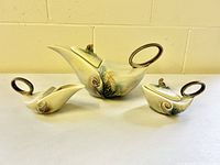 Three-piece set: teapot, creamer, sugar bowl in Aladdin lamp style with parchment and pine glaze, shown from front