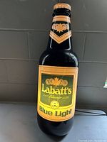Front view of illuminated Labatt's Blue Light beer bottle sign with yellow and green label.