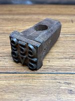 Photo of the iron hammer head stamp showing angled view of the piece and its hollow center for hammer handle attachment.