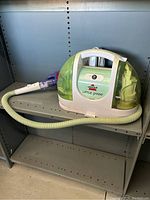 Front and side view of Bissell Little Green wet vac showing overall design, hose, handle, and power switch.