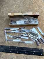 Cutlery set laid out on plywood, showing knives and forks in plastic wrappers and original cardboard box with bubble wrap.