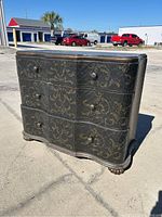 Front and right side view of dresser showing serpentine drawer fronts, stenciled decoration and carved feet
