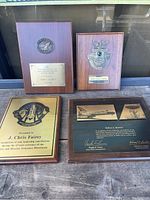 Photo of four NASA service award plaques arranged on wooden surface, showing designs and inscriptions.