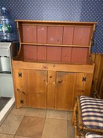 Photo of a wooden buffet cabinet with a hutch on top. The piece has three shelves in the top section and two door cabinets in the bottom section with metal hinges. The wood has a natural finish with some wear marks.