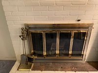 Fireplace, fireplace screen, and fireplace tool stand with tools beside the fireplace.