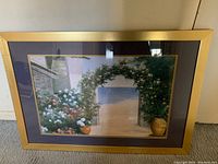 Front view of framed flower arch art with floral and beach scenery visible.