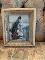 Framed painting showing mother and daughter by a railing, setting suggests an outdoor town or waterfront scene, framed with a cracked patina antique style frame.