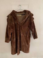Front view of the brown mink fur coat on a hanger showing heavy wear and multiple tears, including holes on the left sleeve.