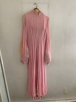 Front view of pink chiffon gown showing full length, one long sleeve stained, beaded bodice detail