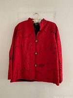 Full view of red Chicos jacket with black embroidery, hanging on hanger.