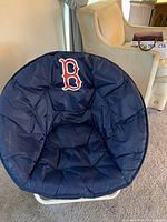 Front view of the foldable Boston Red Sox circular chair showing the padded navy blue cushion and Red Sox logo on the backrest
