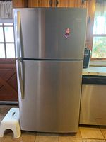 Front view of closed refrigerator showing stainless steel exterior, top freezer door and bottom refrigerator door