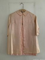 Front view of light pink satin-like jacket with 3/4 sleeves and Peter Pan collar