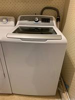 Front view of white GE top load washing machine with closed glass lid.