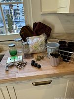 Overview of cabinet hardware, canning jars, planting pots, metal basket, and fabric remnants arranged on countertop.