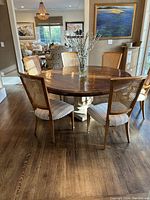 Four cane back dining chairs around a round dining table showing striped upholstery on seats.