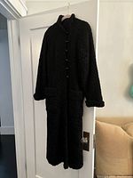 Coat hanging on door, full front view showing overall length and silhouette