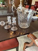 Set on table showing all items: glass wine bucket with silver grapes, pair of small sterling silver candlesticks, frosted crystal golf ball, and crystal swan candle stick holders.