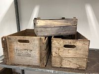 Three weathered wooden crates stacked, showing the text property stamps.