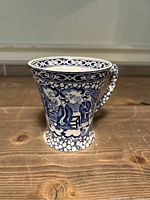 Front side view of the blue and white ceramic mug showing Chinese bird and floral design.