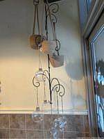 Full view of metal hanging stand with all basket pots and glass terrariums visible from side angle