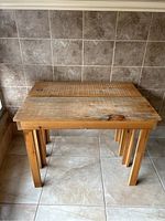 Pair of pine tables nesting with the smaller table pushed under the larger one, both showing sturdy construction and rustic natural pine wood.