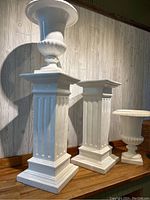 Two pedestal stands and two urns arranged on wooden floor against wall
