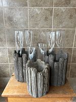 Front view of three woodland style cement vases with clear glass inserts, showing bark-like texture and overall shape.