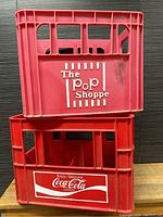 Photo of both vintage pop crates stacked, showing The Pop Shoppe crate on top and Coca-Cola crate below.