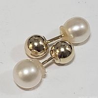 Photo showing the pair of 10K yellow gold reversible earrings each with a freshwater pearl on one side and gold ball on the other.