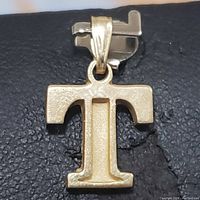Front view of the 10K yellow gold 'T' shaped pendant showing its texture and bail.