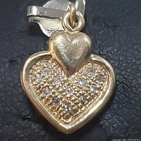 Close-up front view of 14K gold heart pendant with diamond inset showing the smaller solid heart on top and larger heart shape with diamonds inside.
