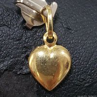 Close-up front view of the small heart-shaped yellow gold pendant, showing smooth polished surface and attached bail.