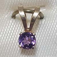 Front view of round faceted amethyst set in 14K yellow gold pendant.