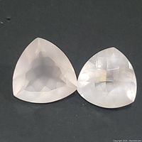 Two faceted rose quartz stones, rounded triangular shape, translucent pale pink, with multiple facets.