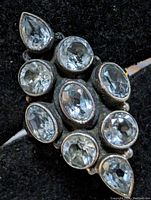 Top and angled close-up views of a sterling silver ring with nine aquamarine stones arranged in an oval cluster.