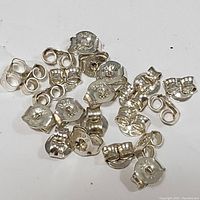 Close-up photo of multiple sterling silver earring backs with various shapes and 925 stamps visible.