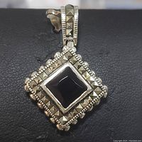 Close-up front view of the sterling silver pendant showing the square garnet center and surrounding marcasite stones.
