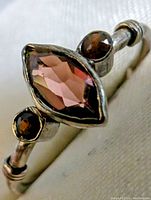 Close-up image showcasing the marquise cut garnet stone flanked by two round garnets in sterling silver setting.