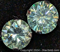 Close-up front view of the two round-cut moissanite stones showing their brilliance and the prong settings in 10K white gold.