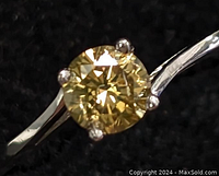 Close-up of brown diamond in four-prong setting against black background
