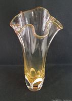 Full view of vintage Adam Jablonski blown art glass vase showing ruffled top and amber coloration with clear glass base.