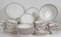 Full set displayed with plates, bowls, cups and saucers showing floral pattern and gold trim.