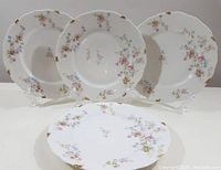 Four antique C. Ahrenfeldt Limoges dinner plates displayed together showing floral pattern and gold rim details
