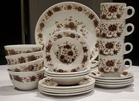 Photo of entire stacked set showing four 10" plates at the back, salad plates and bowls stacked in front, four beverage mugs stacked vertically on the right on top of saucers