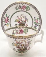 Front view of the teacup and saucer showing floral patterns and gold trim.