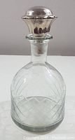 Front view of the vintage glass decanter with silver stopper showing diamond patterning and stopper details.