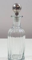 Front view of entire vintage glass decanter showing body, neck, and stainless steel stopper.