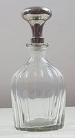Front view of vintage clear glass decanter with stainless steel stopper showing vertical ribbed design and rounded stopper top